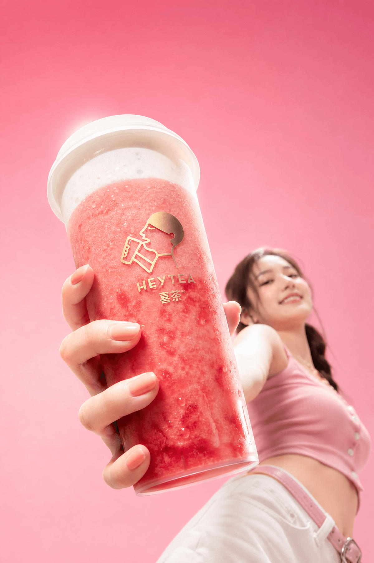喜茶芝芝莓莓 + 亚洲美女 | 粉桃色渐变背景 [镜头] 极端广角低机位仰拍 人物 镜头从模特下方往上打，前景的手…