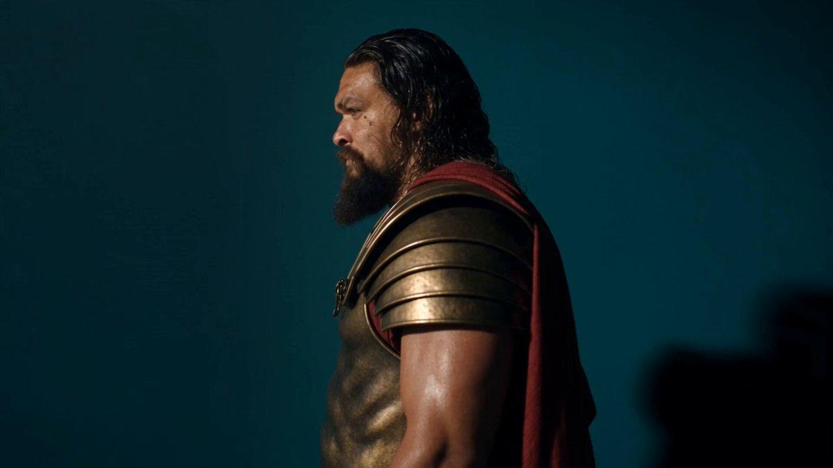 MAIN WARRIOR 是一名完全原创、无法对应任何现成人物的明确成年男性，约四十多至五十岁，高大、极其强壮，weathered olive skin，肩长深色湿发，浓密深色胡须夹杂灰丝，眉骨深刻，面部有污垢、汗水与疲惫痕迹。穿原创 antiqued-bronze cuirass，腹部只有非标志性雕塑甲片、圆钝分层肩甲、深色皮革裙甲、青铜护臂、厚重战靴与低饱和 dark-crimson cloak；不戴头盔。脸、胡须、污迹、盔甲、披风和身体比例全程完全一致。…