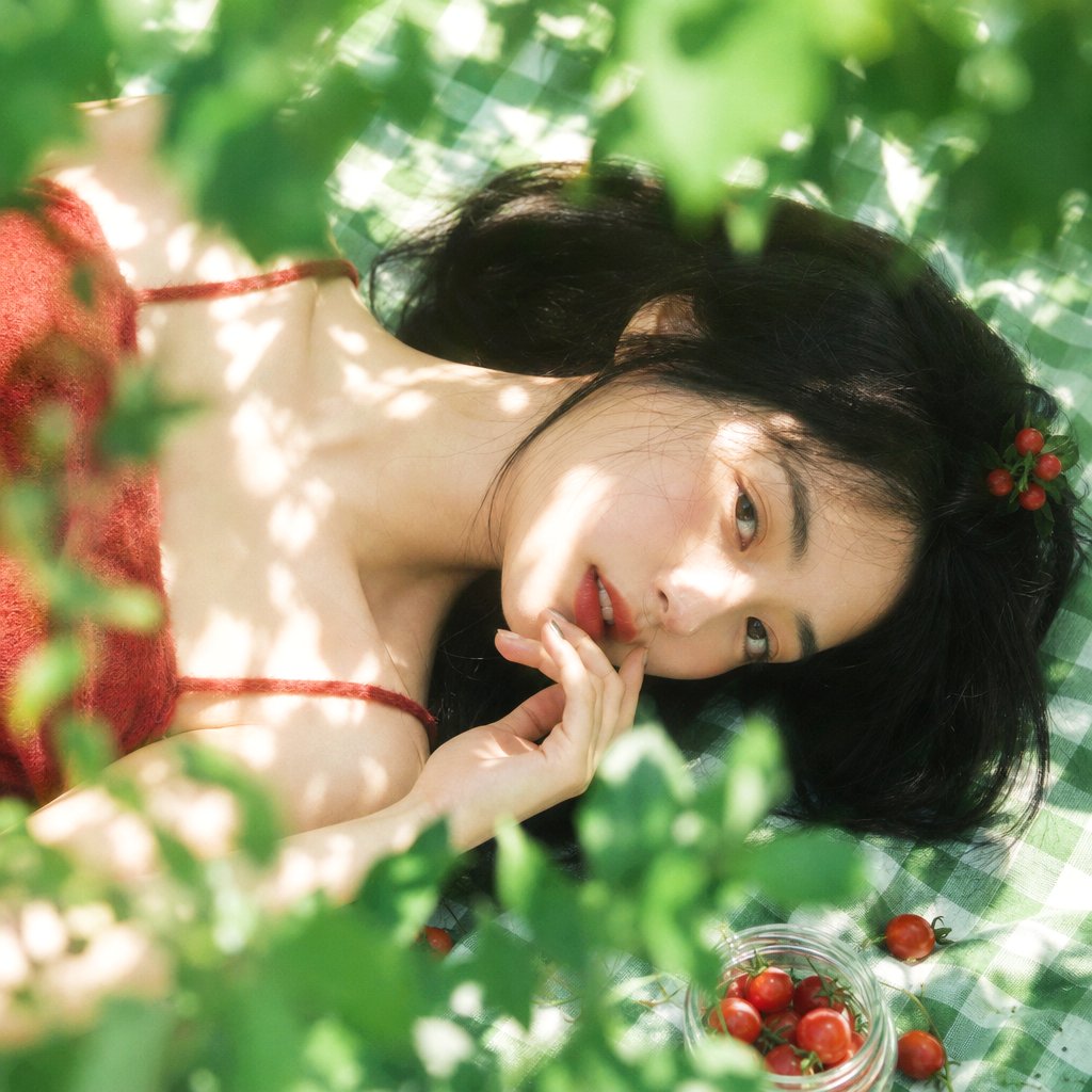 真人摄影,夏日植物系生活方式写真,清透日系胶片感,竖幅 2:3,俯拍近景到面部特写,年轻女性横向躺在绿白格纹野餐布上,脸部位于画面中部偏右下作为主视觉,周围绿植前景占较大比例并形成柔和遮挡,底部少量透明玻璃罐装小番茄与散落番茄作为辅助叙事元素。女性黑色长发铺散在布面 and 颈侧,白皙偏暖象牙肤调,受叶片反光影响阴影微微偏青绿,鼻梁、脸颊、肩颈和手背有斑驳阳光高光;肩颈与手臂线条纤细柔和,身体放松侧躺,头部向右倾斜,一只手自然贴近下巴和唇边,手指轻弯。眼神清澈略迷离,轻微看向镜头方向,嘴唇微张,红润唇色,表情安静克制、若有所思。穿红色短绒针织吊带上衣,衣料柔软蓬松哑光,边缘轻微贴肤并有自然褶皱,头侧有红色果实发饰点缀。自然阳光从上方穿过叶片投射,形成强烈但梦幻的斑驳光影,高光略溢出,阴影偏绿,主色为鲜绿与白绿格纹,红色番茄和红色服装少量撞色点缀;浅景深,前景叶片虚化,低对比柔焦,轻微胶片颗粒,真实皮肤纹理和真实光影