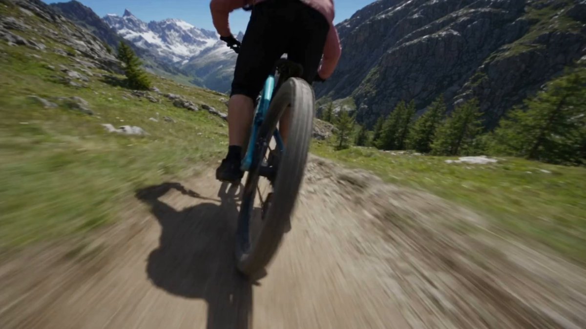 Create an explosive, high-adrenaline extreme mountain-biking action sequence in…